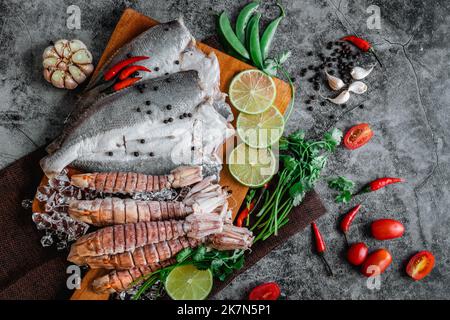 Ein Blick von oben auf rohen frischen Fisch und Krabben, Limetten, Knoblauch, Paprika und Salz auf einem Tisch Stockfoto