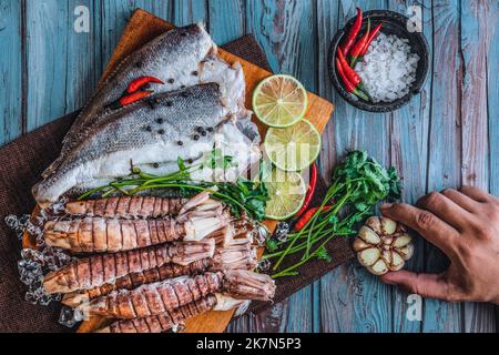 Ein Blick von oben auf rohen frischen Fisch und Krabben, Limetten, Knoblauch, Paprika und Salz auf einem Tisch Stockfoto