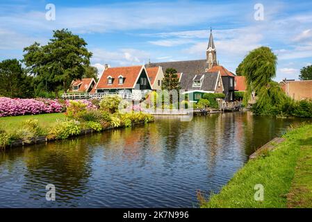 Traditionelle, rote Ziegeldächer am Ufer eines Flusses im malerischen idyllischen Dorf De Rijp in Nordholland, Niederlande Stockfoto