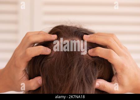 Clos eup Blick auf einen nicht erkennbaren jungen Mann mit langen Haaren, der den Hinterkopf massiert, um Alopezie-Probleme zu lösen Stockfoto