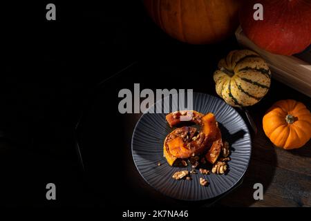 Dunkel launisch bildlich Stillleben von Herbst gerösteten Butternut Kürbis mit Zimt, Walnüssen und Honig bestäubt Stockfoto