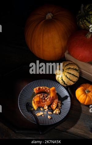 Dunkel launisch bildlich Stillleben von Herbst gerösteten Butternut Kürbis mit Zimt, Walnüssen und Honig bestäubt Stockfoto