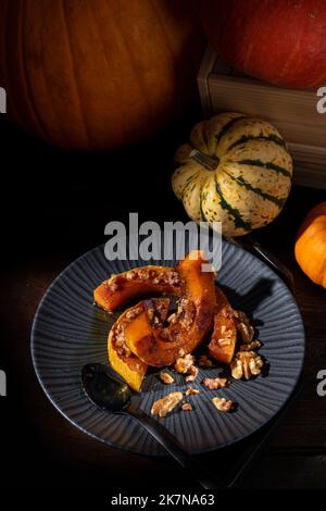 Dunkel launisch bildlich Stillleben von Herbst gerösteten Butternut Kürbis mit Zimt, Walnüssen und Honig bestäubt Stockfoto