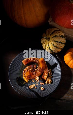 Dunkel launisch bildlich Stillleben von Herbst gerösteten Butternut Kürbis mit Zimt, Walnüssen und Honig bestäubt Stockfoto