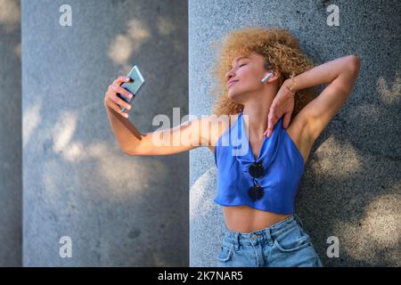 Junge brasilianische Frau mit Ohrhörern, die Musik hören und tanzen. Stockfoto