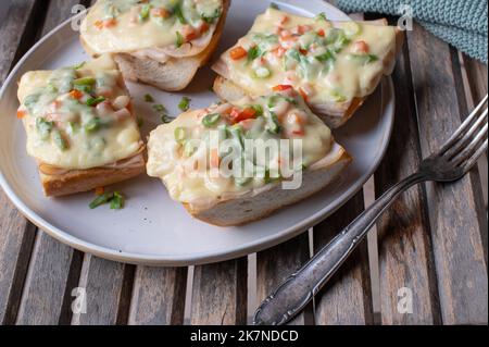 Gegrilltes Schinken- und Käsesandwich auf französischem Baguette mit Schnittlauch und Paprika Stockfoto