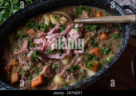 Linsensuppe mit Schweinefleisch in einem altmodischen Topf. Nahaufnahme Stockfoto