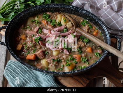 Linseneintopf mit Schweinefleisch in einem rustikalen und altmodischen Topf. Traditionelles deutsches Gericht Stockfoto