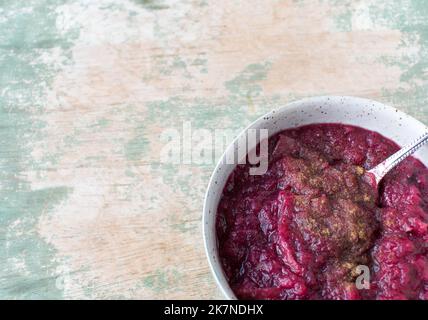 Gesundes Fruchtdessert mit geschmorten Äpfeln, Heidelbeeren und Zimt in einer Schale isoliert auf Holztisch mit Kopierraum Stockfoto