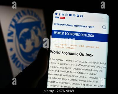 Person, die Mobiltelefon mit der Webseite der UN-Agentur Internationaler Währungsfonds (IWF) auf dem Bildschirm vor dem Logo hält. Konzentrieren Sie sich auf die Mitte des Telefondisplays. Stockfoto