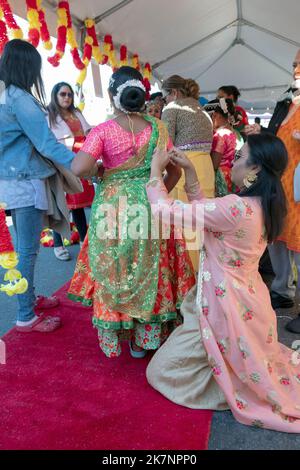 Bei der Diwali-Feier 2022 in Queens, NY, bekommt eine junge Tänzerin Anpassungen an ihrem Kostüm. An der Liberty Avenue in South Richmond Hill, Queens, NYC. Stockfoto