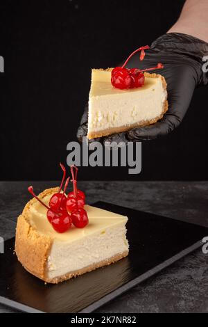 Klassischer Käsekuchen mit Kirschen auf dunklem Hintergrund. Stockfoto