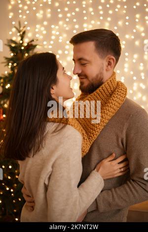 Zwei fröhliche schöne süße zart schöne liebenswert niedlich romantisch verheiratet Ehegatten Mann und Frau in einem Snood fot zwei in der Nähe von Tannenbaum im Haus einfaltet Stockfoto