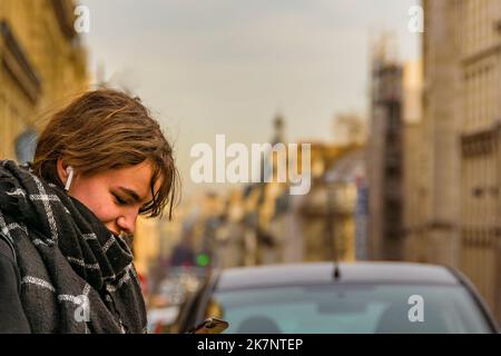 PARIS, FRANKREICH, JANUAR - 2020 - Mittelaufnahme der urbanen Szene junge attraktive Frau, die sein Smartphone beobachtet, paris, frankreich Stockfoto
