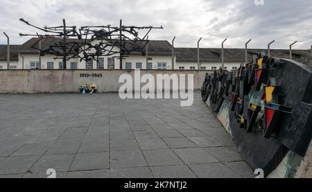 Dachau, Deutschland. 18. Oktober 2022. Die Bronzeskulptur 'Menschen im Stacheldraht' steht auf dem apellplatz des ehemaligen Konzentrationslagers. Das Denkmal, das der Künstler Nandor Glid 1967 geschaffen hat, wurde nach mehr als drei Jahren Restaurierung neu eingeweiht. Quelle: Stefan Puchner/dpa/Alamy Live News Stockfoto