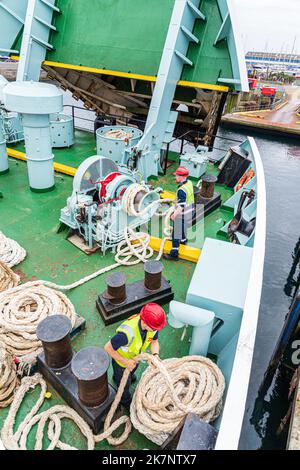 Deckshände, die Festmacherseile auf der CalMac-Fähre Isle of Arran aufwickeln, verlassen Ardrossan, North Ayrshire, Schottland, Großbritannien, um nach Campbeltown zu gelangen Stockfoto