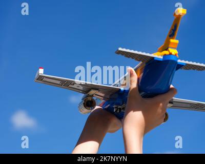 Tambow, Russische Föderation - 30. Juni 2022 Ein Kind hält ein Lego-Passagierflugzeug gegen den blauen Himmel Stockfoto