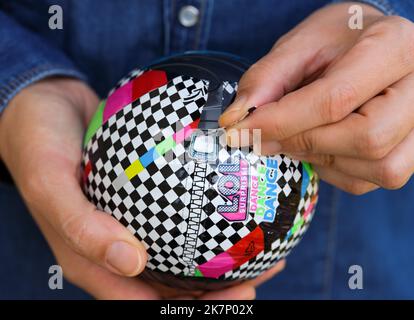Tambow, Russische Föderation - 02. Oktober 2022 Eine Frau, die die Verpackung eines LOL Surprise Dance Dance Balls mit Puppe darin schält. Stockfoto