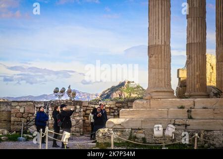 2018 01 03 Athen Griechenland - Touristen auf Akropolis fotografieren Ruinen mit dem Hügel Lycabethus und der Kirche des Agios Georgios, die im Hintergrund sichtbar ist R Stockfoto