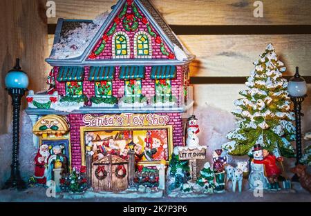 Szene aus dem Weihnachtsdorf mit Weihnachtsmännern und Kindern und Hunden draußen im Schnee - konzentrieren Sie sich auf das Gebäude Stockfoto