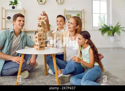 Eine glückliche Familie mit zwei Kindern spielt zu Hause auf dem Boden im Turm. Stockfoto