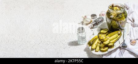 Eingelegte Gurken für Winter-Bio-Lebensmittel. Krug mit hausgemachten Gurken, sauberes Essen, veganes Konzept. Trendiges hartes Licht, dunkler Schatten, weißer Gips-Backgr Stockfoto