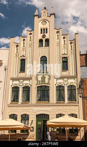 Deutschland, Wismar - 13. Juli 2022: An der Wasserkunt Building beige dekorierte Stufenfassade am Marktplatz, Marktplatz, ist Bar Restaurant mit Wandmalereien U Stockfoto