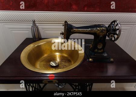 Grodno, Weißrussland - 13. Oktober 2017: Ein Waschbecken aus einer alten Singer Nähmaschine in der Faraday Bar. Das Wasser schaltet sich automatisch ein, wenn die h Stockfoto