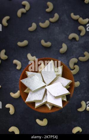 Kaju Katli ist eine diamantförmige indische Süßigkeit, die aus Cashew-Zucker und mava auf einem Teller mit launischem Hintergrund serviert wird Stockfoto