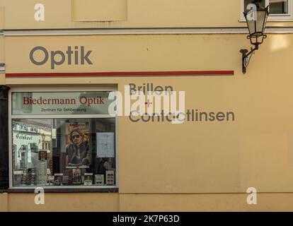 Deutschland, Wismar - 13. Juli 2022: Gelbe Fassade von Biedermann Optik, Optikergeschäft in der Darkwartstraße. Objektive und Brillen auf dem Display hinter WIN Stockfoto