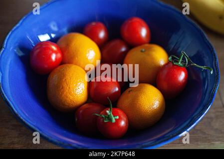 Kirschtomaten und Mandarinen in einer blauen Schüssel. Stockfoto