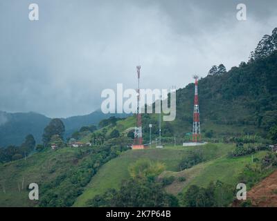 An einem wolkigen Tag stürmen die Telekommunikationstürme auf den grünen Hügeln Stockfoto