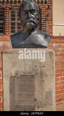 Deutschland, Wismar - 13. Juli 2022: St. Marienkirche. Nahaufnahme der Büste von Gottlob Frege auf der Ostseite des Geländes. Rote Steine als Hintergrund. Stockfoto