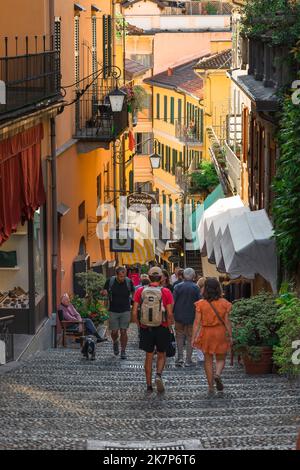 Bellagio Straße Altstadt, Blick auf Menschen, die in einer malerischen alten Straße im Zentrum von Bellagio, einer beliebten Stadt am Comer See, Italien, spazieren gehen Stockfoto