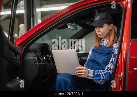 Frau Auto Mechaniker tun Diagnose im Auto mit Laptop. Stockfoto