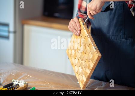 Ein erfahrener Holzarbeiter, der auf dem Holztisch eine Strohdose herstellte Stockfoto