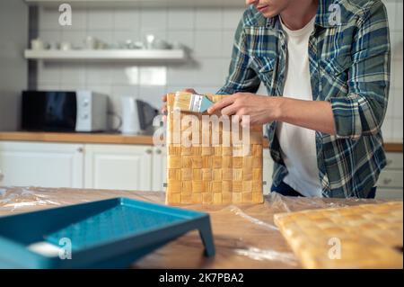 Mann malt die Seitenstücke der Schachtel auf dem Küchentisch Stockfoto