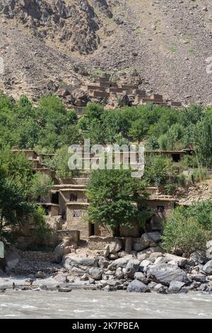 Vertikale Ansicht des abgelegenen traditionellen afghanischen Dorfes auf der Bergseite entlang des Flusses Panj aus dem Darvaz-Bezirk in Gorno-Badakshan, Tajikistan Pamir Stockfoto