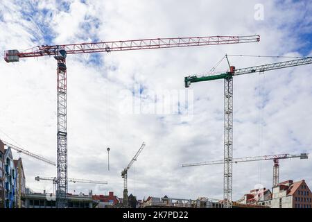 Mehrere hohe Turmdrehkrane auf städtischen Baustellen vor bewölktem Himmel Stockfoto