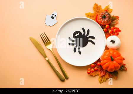 Herbsttischeinstellung. Weißer Teller, goldenes Besteck und Herbstdekorationen. Stockfoto