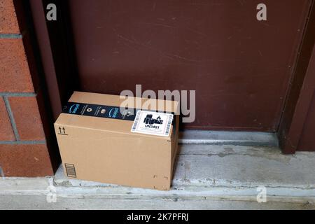 Eine Amazon-Lieferung liegt vor der Haustür. Ein UN 3481-Aufkleber auf dem Karton zeigt den Inhalt an, der Lithium-Ionen-Batterien enthält Stockfoto