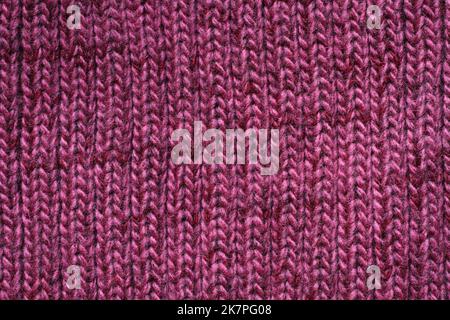 Strickstruktur in lila melierter Wolle. Makro. Stockfoto