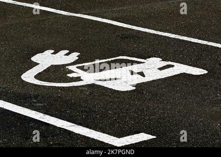 Ein Parkplatz, der für das Aufladen von Elektrofahrzeugen markiert ist. Das Schild auf dem Asphalt zeigt, dass der Platz für ein Elektrofahrzeug zum Laden und Parken ist. Stockfoto