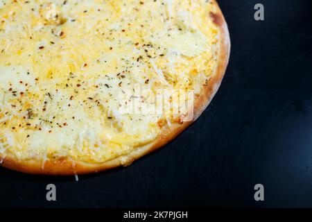 Köstliche Pizza mit vier Käsesorten, Cheddar, Parmesan, Mozzarella und Tomatensauce auf schwarzem Hintergrund. Blick von oben. Stockfoto