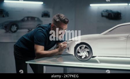 Senior Automotive Design Engineer verwendet ein Drehwerkzeug zur Perfektionierung der Rake-Skulptur eines Automodells in einem High-Tech-Unternehmen. Ein Ingenieur mit Schutzbrille arbeitet in einem Automobilunternehmen. Stockfoto