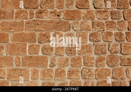 Vorderansicht der Steinmauer Hintergrund. Die Steine sind hellorange in der Farbe. Stockfoto