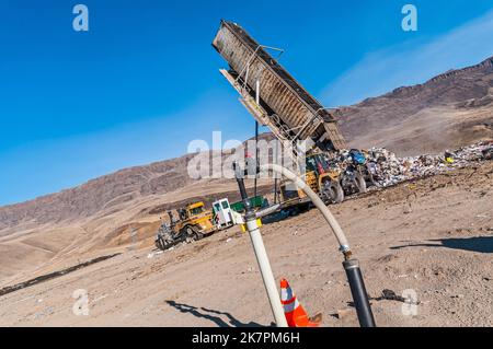 Eine vertikale Deponie Methangasbrunnen an einer aktiven Deponie, die einen Anhängerkipper im Hintergrund zeigt. Stockfoto