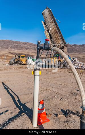 Eine vertikale Deponie Methangasbrunnen an einer aktiven Deponie, die einen Anhängerkipper im Hintergrund zeigt. Stockfoto