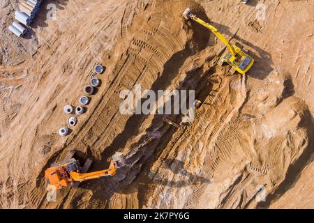 Bagger graben Graben auf der Baustelle, um Rohre für unterirdische Sturmwasserkanäle zu verlegen, die sie verbinden Stockfoto