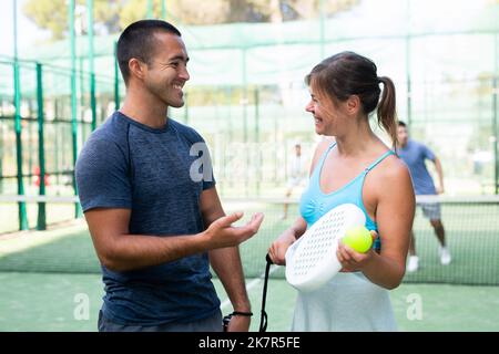 Fröhlicher Mann und Frau paddeln Tennisspieler im offenen Feld Stockfoto